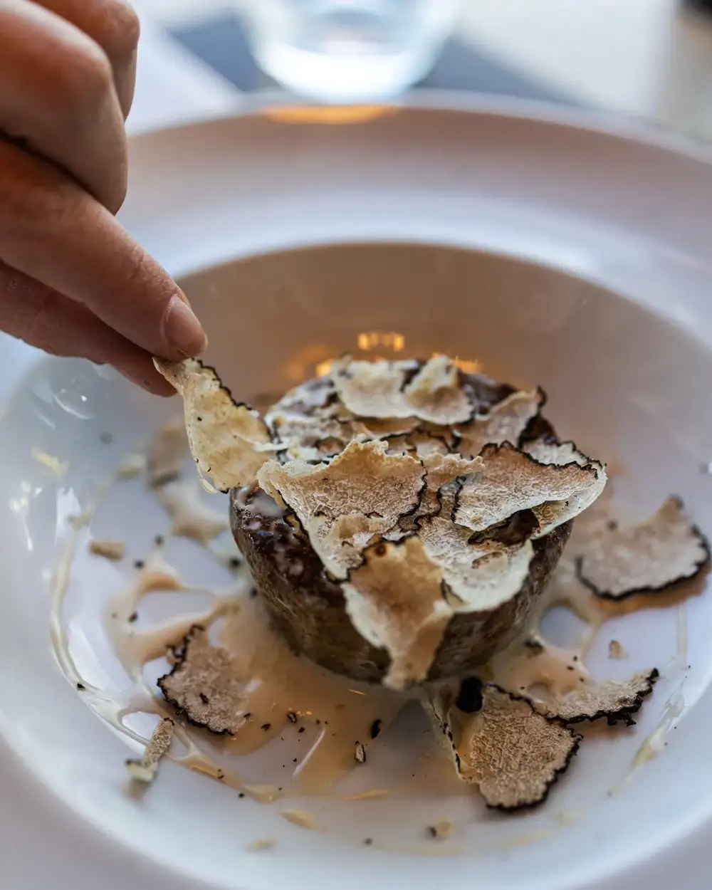 Tartufo fresco affettato a mano sullo sformato di melanzane e porcini